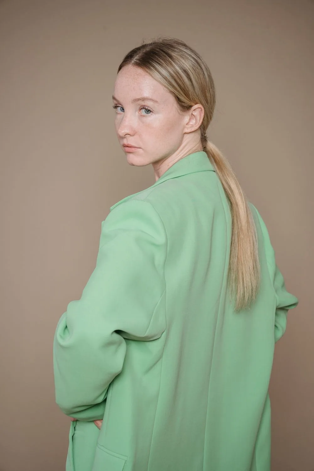 Woman wearing a light green blazer; representative clothing image. Representative image, not a photograph of Green Satin Blazer.