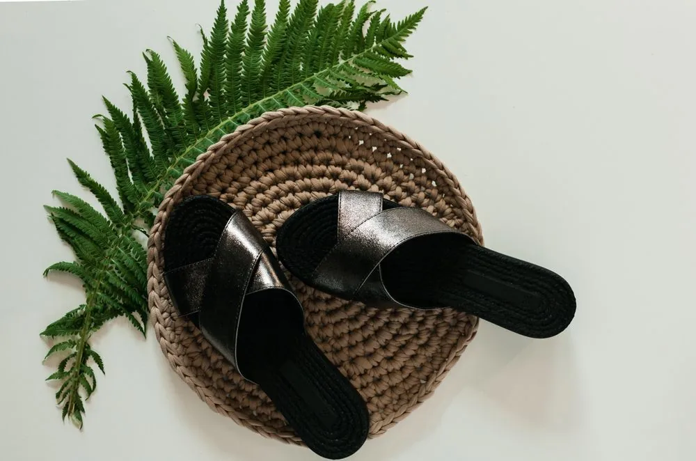 Black cross-strap open-toe slides on a woven mat; representative footwear image. Representative image, not a photograph of Dior Slides.